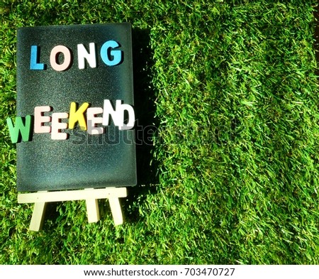 chalkboard with wooden alphabet word "long weekend" on green grass nature background concept for holiday, vacation,schedule,travel