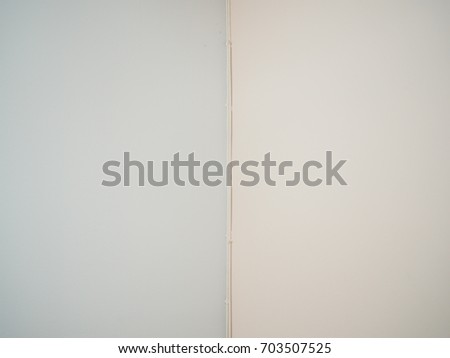 Light blue and pale pink pastel painted cement wall and ceiling, with some dirt and power cord in the geometric perfect middle