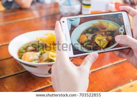People use smart phone for taking photo pink seafood flat noodles. food thai style.