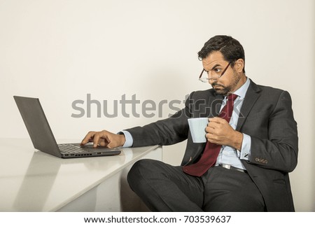 arab man in formalware working in  his computer in a kitchen of his urban apartment