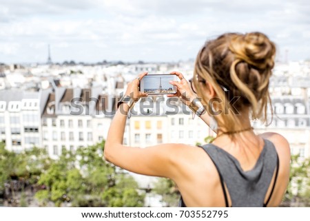 Young woman tourist photographing with phone beautiful skyline in Paris