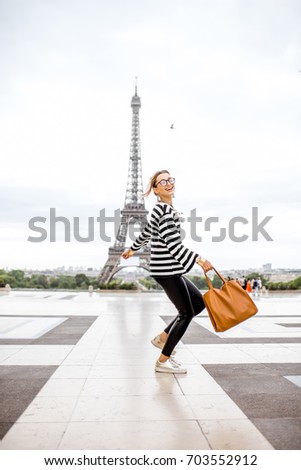 Lifestyle portrait of a stylish woman jumping on the famous square with eiffel tower on the background in Paris
