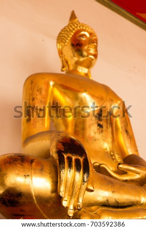 A golden Buddha statue in a public public Buddhist temple focused on his hand