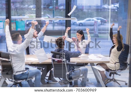 Group of young business people throwing documents and looking happy while celebrating success at their working places in startup office