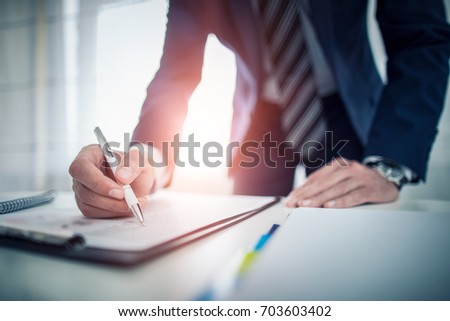 Business man signing contract document on office desk, making a deal.