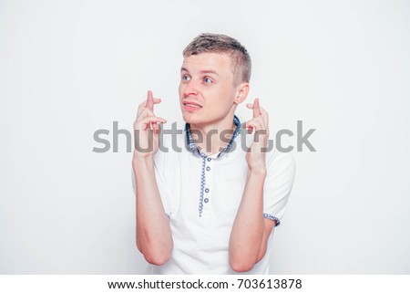A young businessman crossing his fingers in hope, isolated on white background