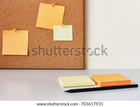 Colorful sticky notes on cork bulletin board with pencil