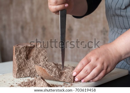 Cook breaks off piece of aerated chocolate for decoration of delicious desserts in restaurant. Process of making culinary art, close up picture