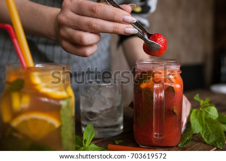 Waiter preparing strawberry cocktail in restaurant. Fresh citrus and berry cold drink with mint and ice on wooden table, concept of refreshment and satisfying thirst, close up picture