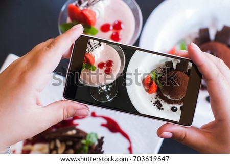 Food photography of sweet desserts by smartphone in restaurant. Creamy strawberry souffle and chocolate fondant, photo shoot and new technology, close up pov picture