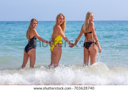 Three blond dutch girls standing hand in hand in sea water