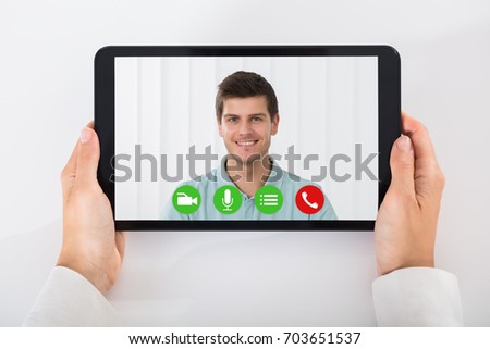 High Angle View Of A Businessperson Videoconferencing With Happy Male Colleague On Digital Tablet Royalty-Free Stock Photo #703651537