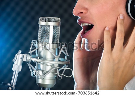 Close-up Of A Female's Open Mouth With Red Lipstick In Front Of Microphone