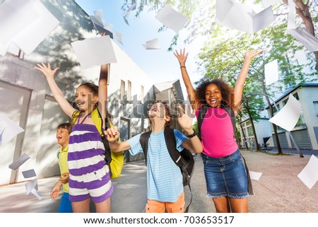Kids throw paper in the air with sheets flying Royalty-Free Stock Photo #703653517