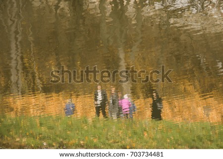 abstract blurred image - reflection of autumn trees and people in water