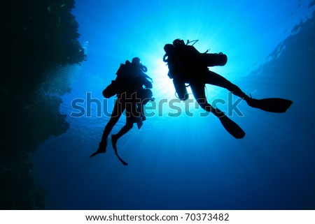 Deep Explorer Technical Divers silhouetted against sunburst Royalty-Free Stock Photo #70373482
