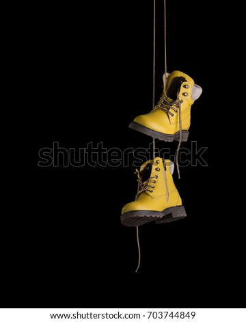 Timberland boots of yellow color hang on laces. Royalty-Free Stock Photo #703744849