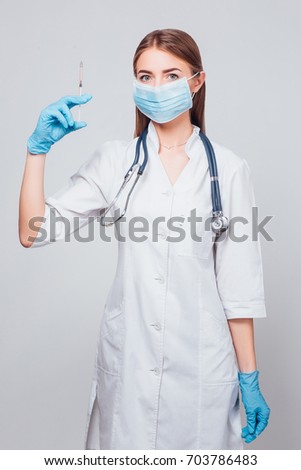 Handsome intelligent doctor holding a syringe in his hands, isolated on a gray background