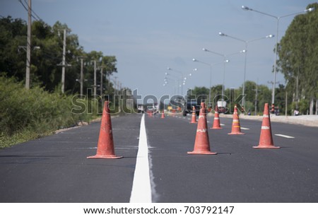Red cone blocks the work area on the asphalt road, Red cone placed on a roadside hazard, Street with traffic cone