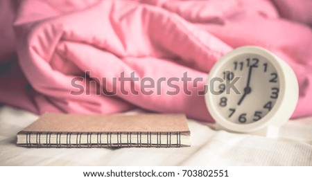 diary on bed with alarm clock and blanket