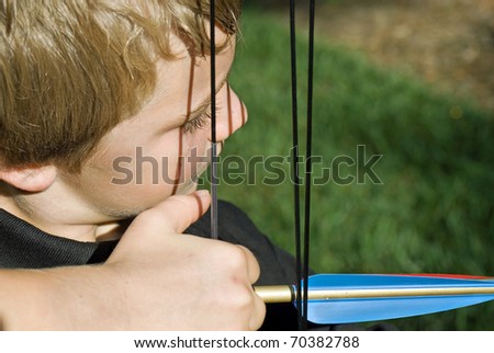 Close up of a boy ready to pull the bow to shoot and arrow. Royalty-Free Stock Photo #70382788