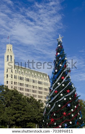 A Christmas tree decked out in red, white and blue stars of Texas stands in Alamo Plaza, with the Gothic architecture of the Emily Morgan Hotel building dominating the San Antonio skyline.