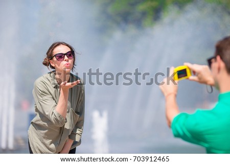 Man taking a picture of his friend while sitting next to a fountain