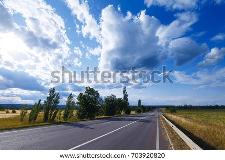 Empty asphalt highway between meadows and fields