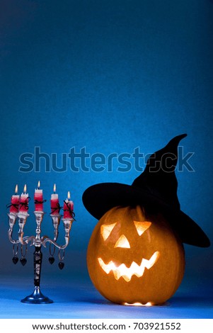 Halloween pumpkin with a candlestick, funny face face on a blue background.