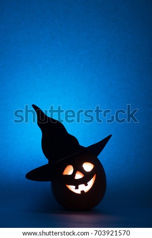 Halloween pumpkin, silhouette of funny face on blue background.