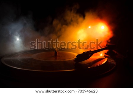 Turntable vinyl record player. Retro audio equipment for disc jockey. Sound technology for DJ to mix & play music. Vinyl record being played against burning fire background with smoke
