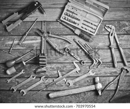 Variety of tools on the old wooden table. Wrench, screwdriver, hammer and others. Black and white photography. Top view.
