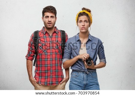 Traveling, tourism and traveling concept. Picture of unhappy young Caucasian man and woman with rucksack and photo camera traveling abroad, feeling worried, facing obstacles during their journey