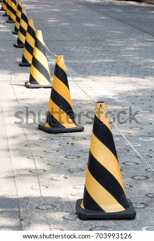 Yellow and black color traffic cone with the rope to guide the permission area on concrete background