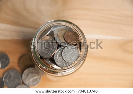 Coins in a glass jar on a wooden background,finance