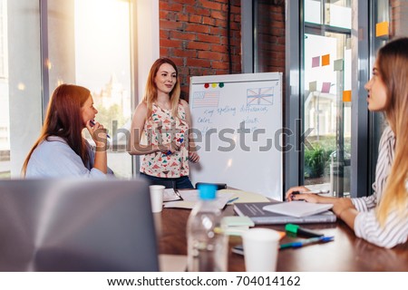 Young woman teaching English to adult students at language school Royalty-Free Stock Photo #704014162