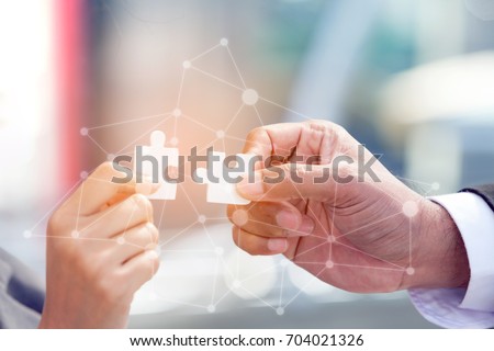 Business People Assembling Jigsaw Puzzle and present Teamwork Support in Office with Digital layer Business Strategy and Social Media Diagram, Partnership Sale Team 
 Collaborate With  Competitors  Royalty-Free Stock Photo #704021326