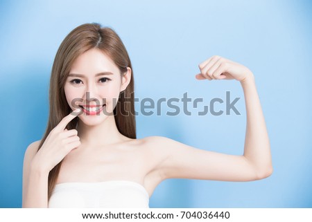 beauty woman show her tooth with strong arm on the blue background