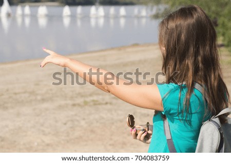 Woman traveller with compass in hand points by finger right direction. Travel concept.