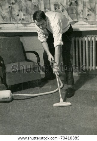 Vintage photo of young man vacuuming (circa 1960)