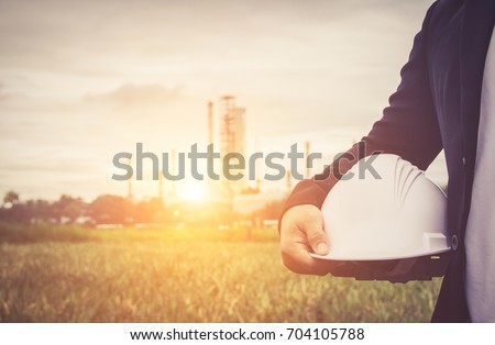 engineer suit white helmet for security standing against oil refinery plant in heavy petrochemical industry estate  Royalty-Free Stock Photo #704105788