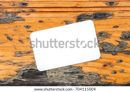 A photo of a blank white business card with rounded edges on a rustic wooden texture. A mockup or a minimalist banner with copy space