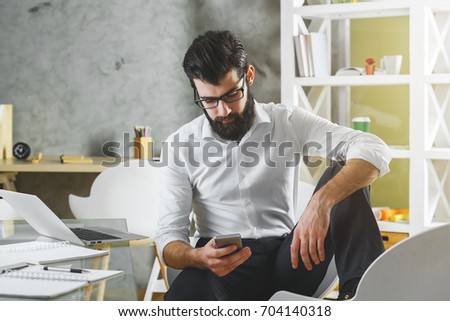 Businessman using laptop and cellphone in modern office. Technology concept 