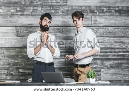 Portrait of two handsome businessmen praying in modern office. Teamwork and partnership concept 