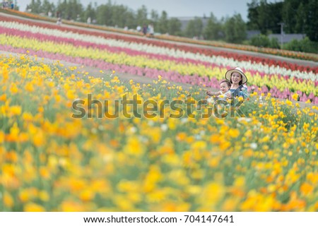 An emotional picture of the 1-year-old baby and her mother feeling happy together in a flower field. A Little girl and young mother enjoying colorful flower field in Hokkaido. Japan.