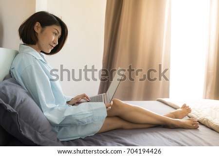 Asian woman using laptop computer on a bed in her room. concept for freelance and digital nomad