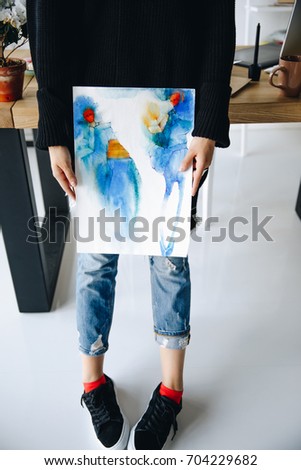 cropped shot of young fashion designer holding watercolor sketch at workplace