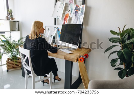 attractive young fashion designer using graphic tablet and desktop computer at workplace