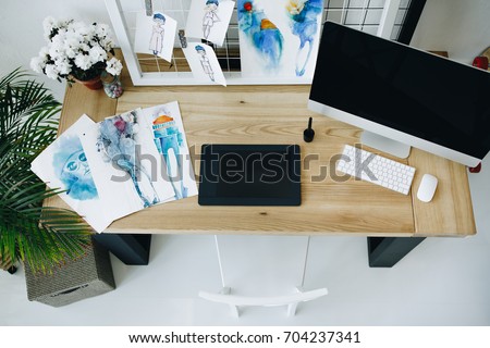 high angle view of graphic tablet, desktop computer and sketches in fashion design studio