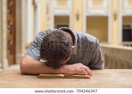 Young student guy studying a boring subject in university